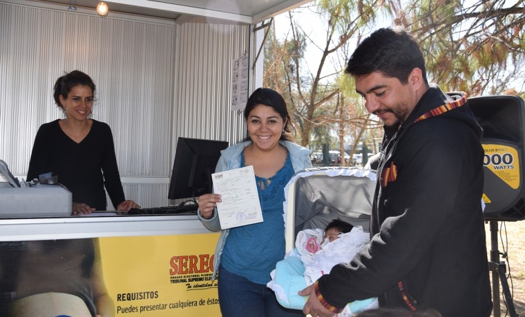 6. Padres de familia exhiben el certificado de nacimiento registrado en la caseta inaugural en Cercado, Cochabamba.