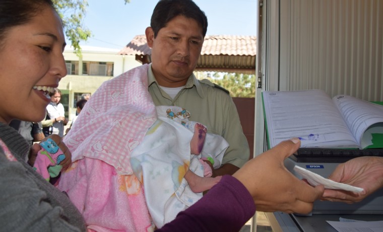 7. Una madre de familia recibe los documentos de su hijo después de registrarla en la caseta registral en Cercado, Cochabamba.